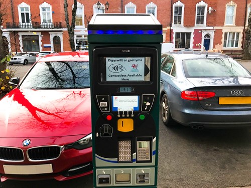 Parking meter between two on-street bays with redbrick houses in the background